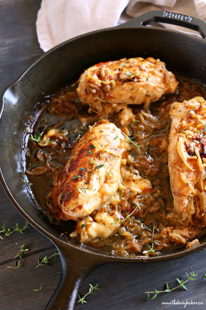 Easy One Pan French Onion Stuffed Chicken in cast iron skillet with caramelized onions and fresh thyme sprigs