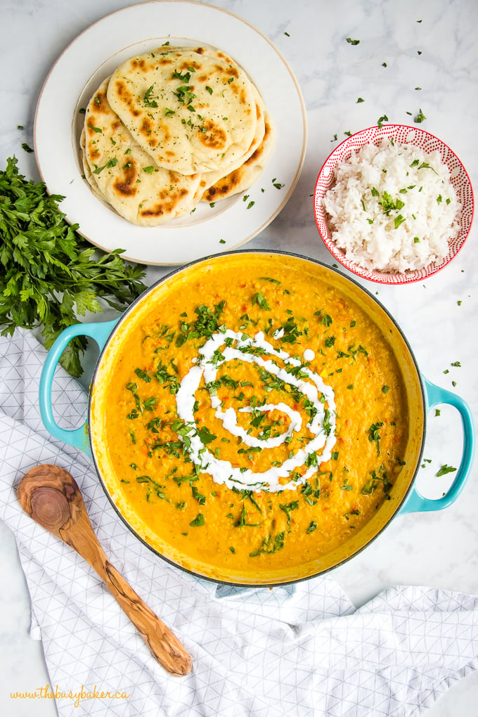 Easy One Pan Lentil Daal Curry with wooden spoon, rice and naan bread