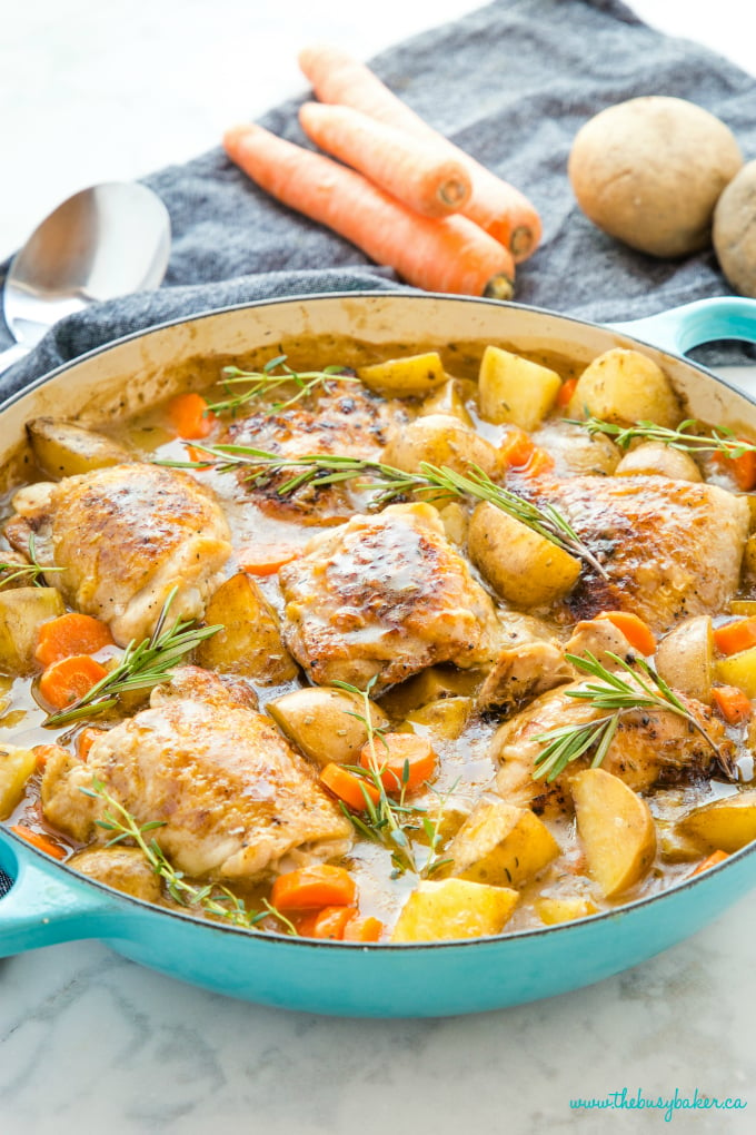 Easy One Pot Roasted Chicken Dinner in turquoise pan with fresh herbs, carrots and potatoes