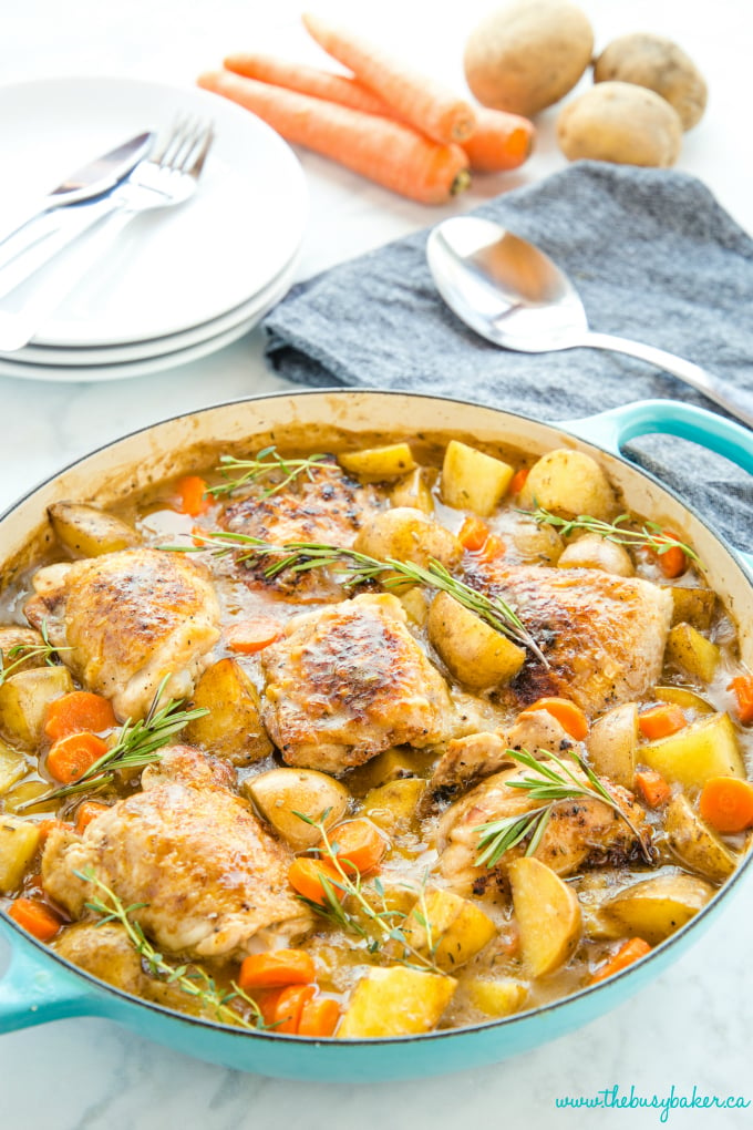 Easy One Pot Roasted Chicken Dinner in turquoise pan with carrots and potatoes and fresh herbs
