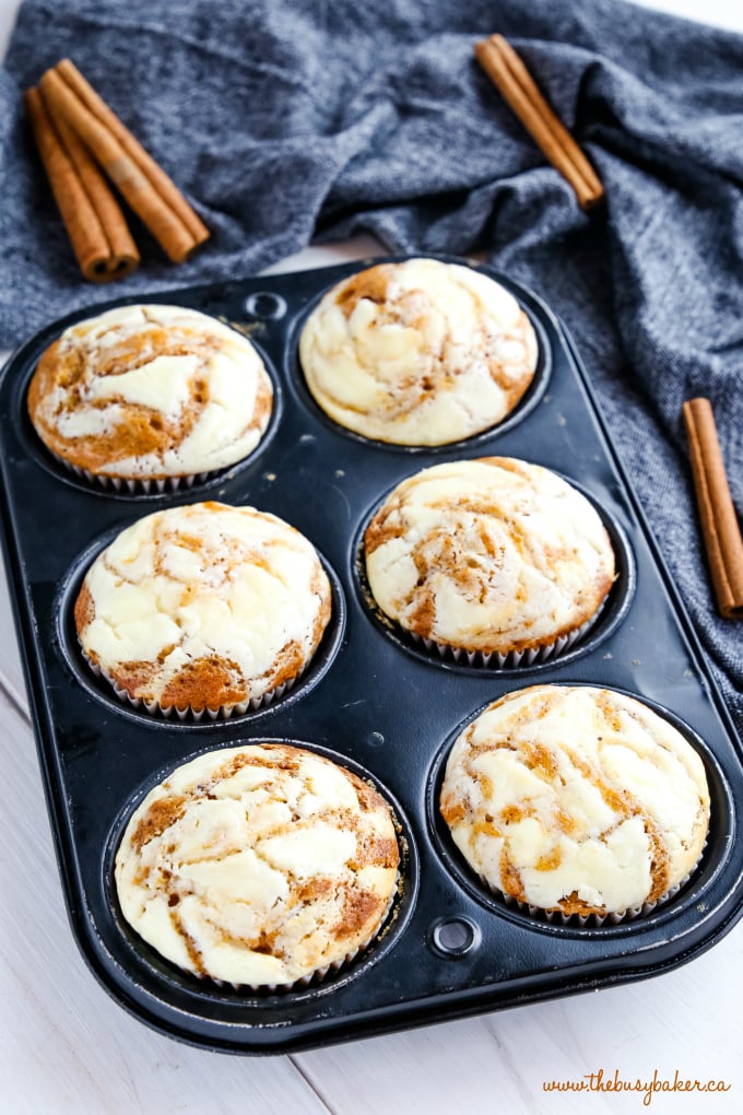 Pumpkin Cheesecake Swirl Muffins in muffin tin with cinnamon sticks