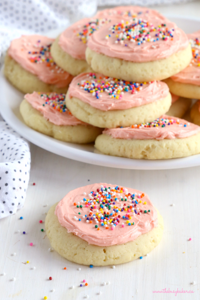 Soft and Chewy Frosted Sugar Cookies on plate with pink frosting and sprinkles