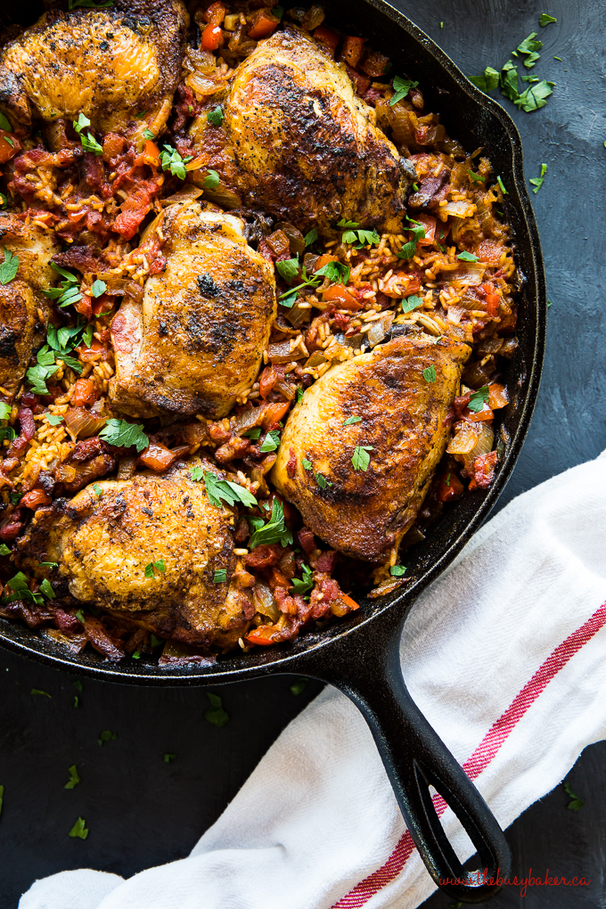 One Pan Spanish-Style Chicken and Rice in cast iron skillet with white kitchen towel