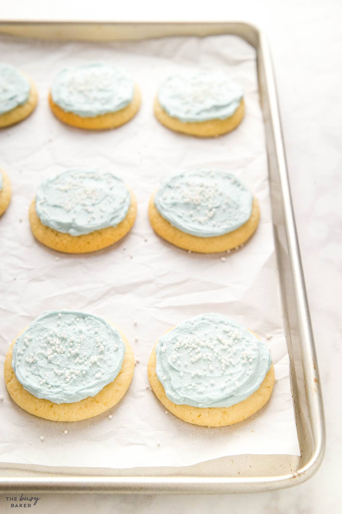 sugar cookies on baking pn with blue frosting and sprinkles