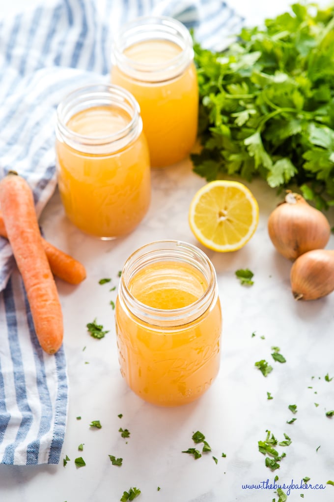 Easy Homemade Chicken Stock in mason jars with onions, lemon, herbs, and carrots