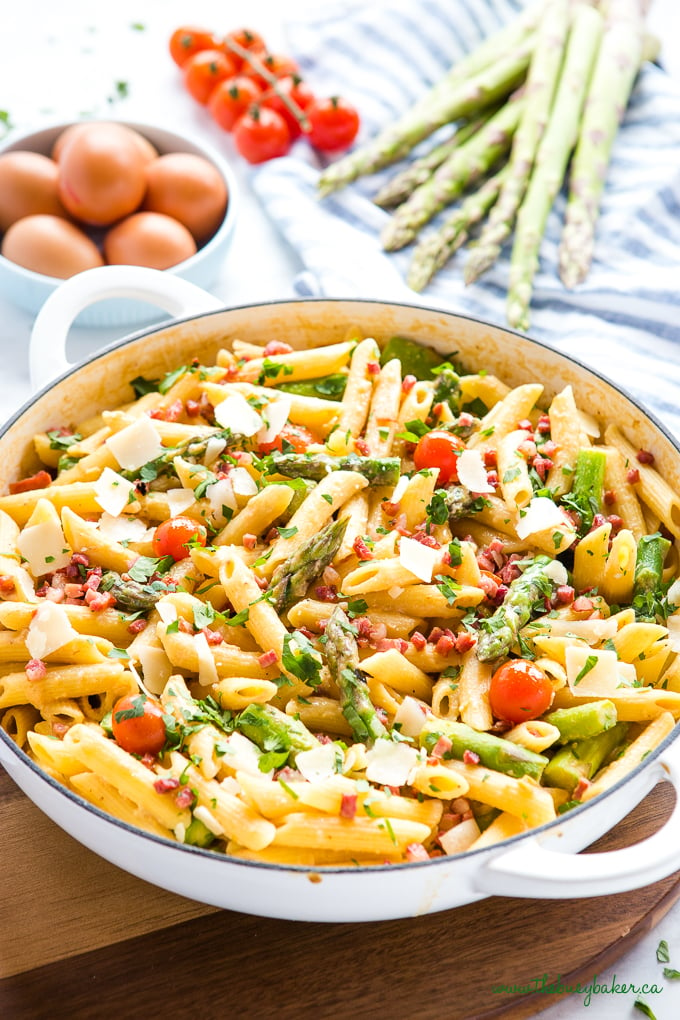 Easy 20-Minute Tomato Asparagus Carbonara Pasta in white casserole dish with fresh veggies and bacon