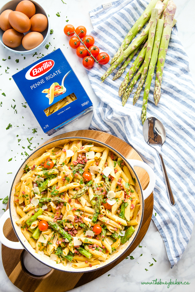 Easy 20-Minute Tomato Asparagus Carbonara Pasta in white casserole dish with fresh veggies and bacon