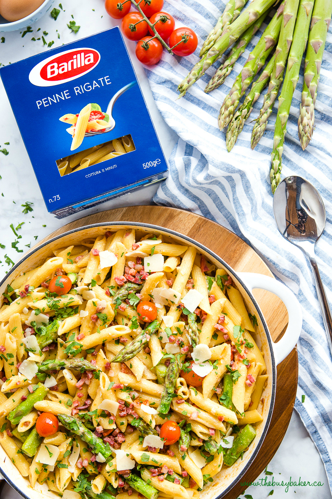 Easy 20-Minute Tomato Asparagus Carbonara Pasta in white casserole dish with fresh veggies and bacon