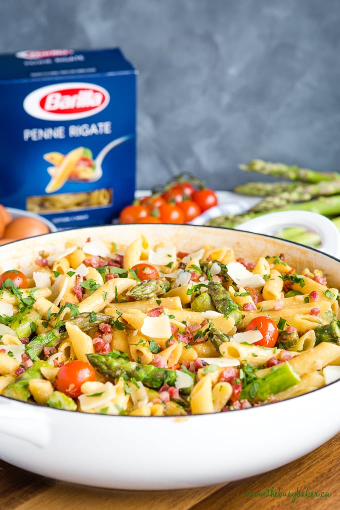 Easy 20-Minute Tomato Asparagus Carbonara Pasta in white casserole dish with fresh veggies and bacon