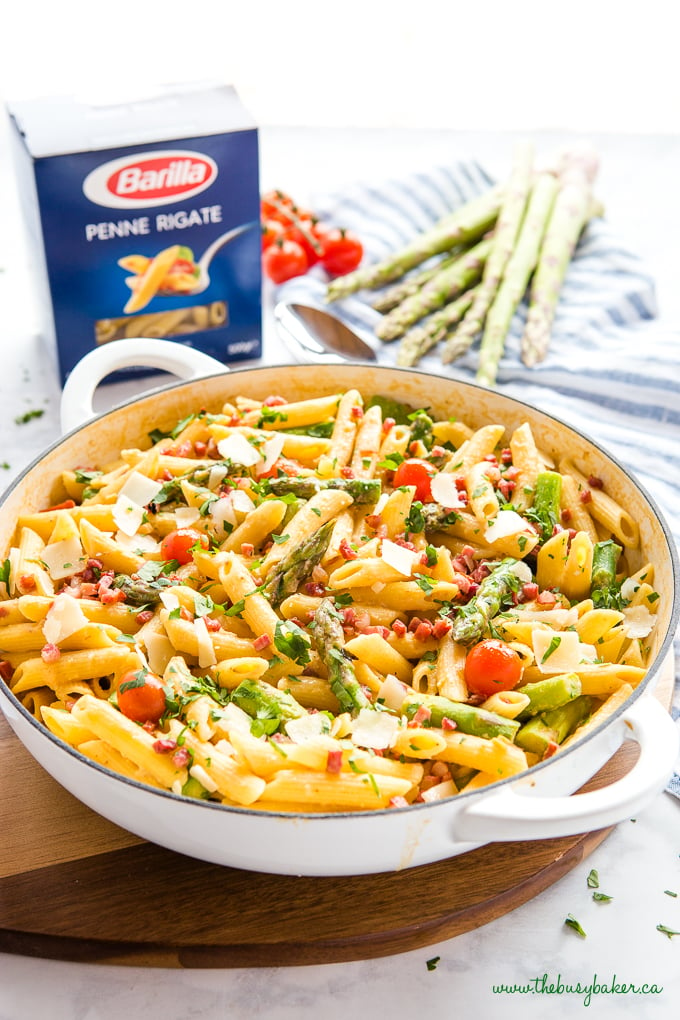 Easy 20-Minute Tomato Asparagus Carbonara Pasta in white casserole dish with fresh veggies and bacon