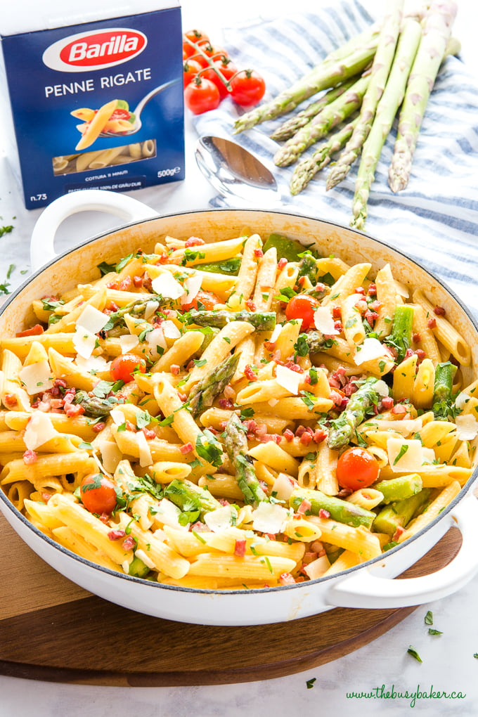 Easy 20-Minute Tomato Asparagus Carbonara Pasta in white casserole dish with fresh veggies and bacon