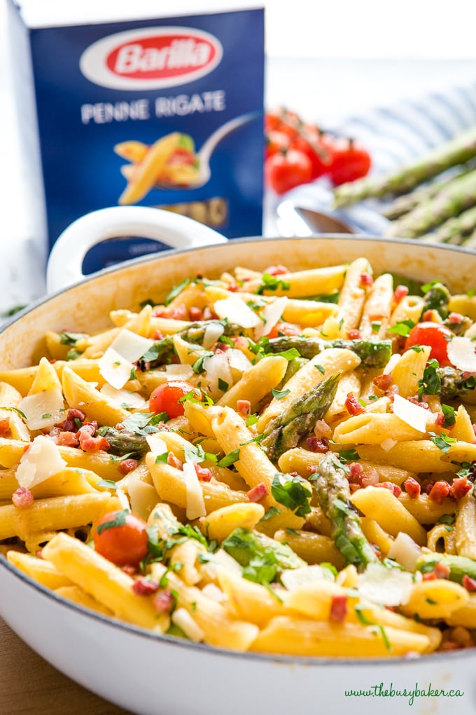 Easy 20-Minute Tomato Asparagus Carbonara Pasta in white casserole dish with fresh veggies and bacon