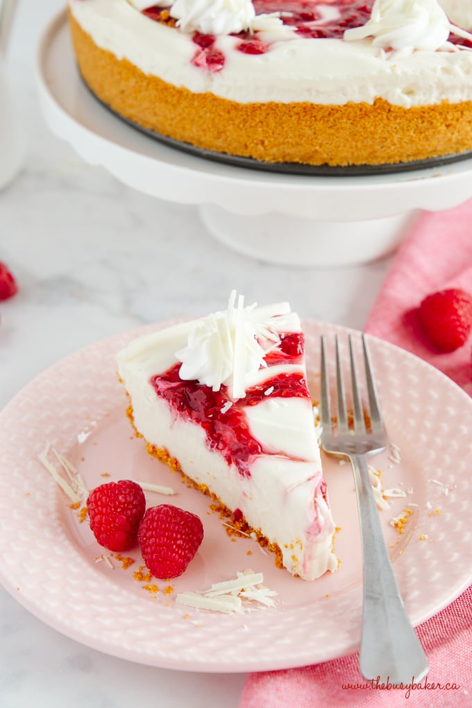 Easy No Bake White Chocolate Raspberry Cheesecake on pink plate with fork and fresh raspberries