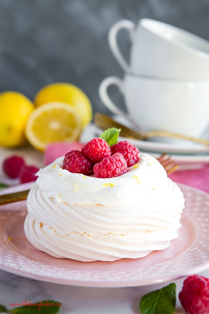 Lemon Raspberry Meringue Nests with fresh raspberries, lemon whipped cream on pink plate with gold fork