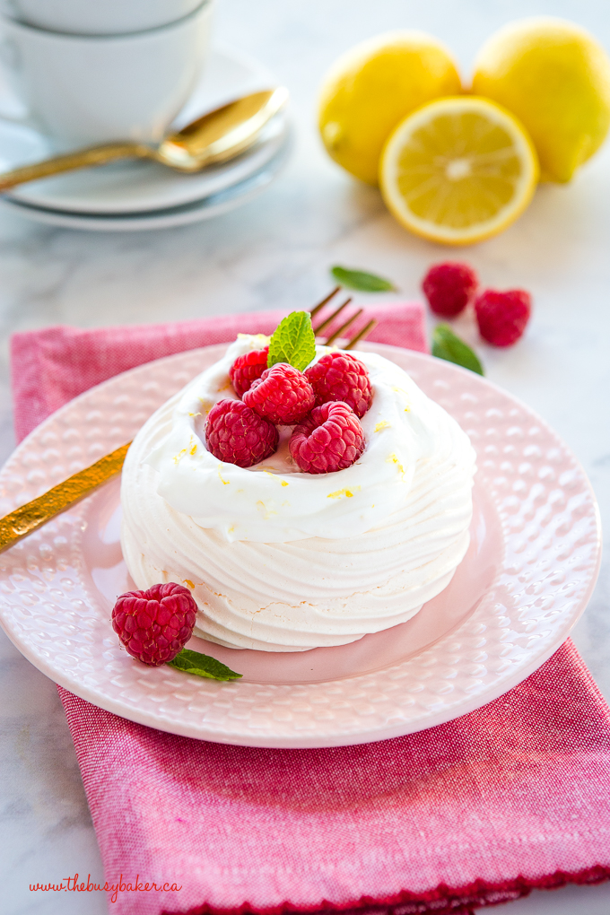 Lemon Raspberry Meringue Nests with fresh raspberries, lemon whipped cream on pink plate with gold fork