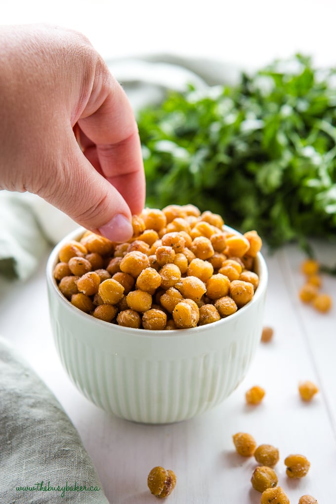 hand reaching for ranch roasted chickpeas in green bowl