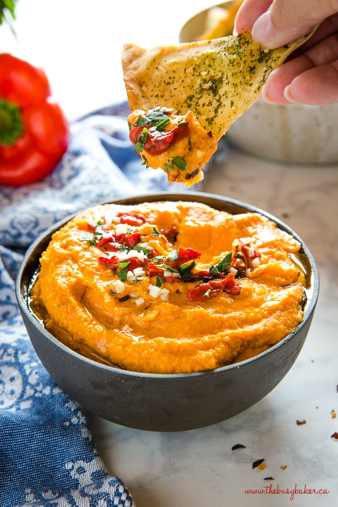Dipping pita chip in roasted red pepper hummus