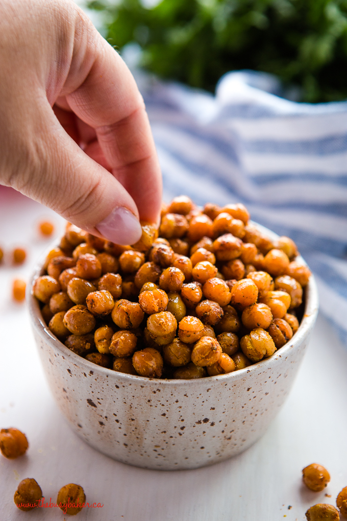 hand reaching for barbecue roasted chickpeas in pottery bowl