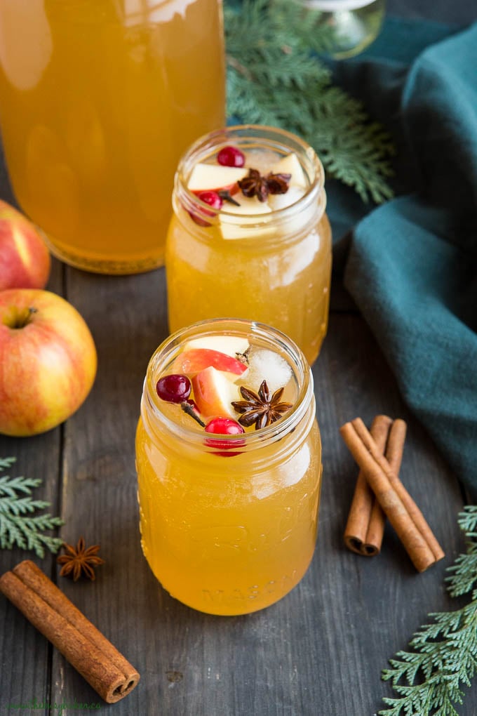 2 holiday cocktails made with apple cider and wine in mason jar glasses