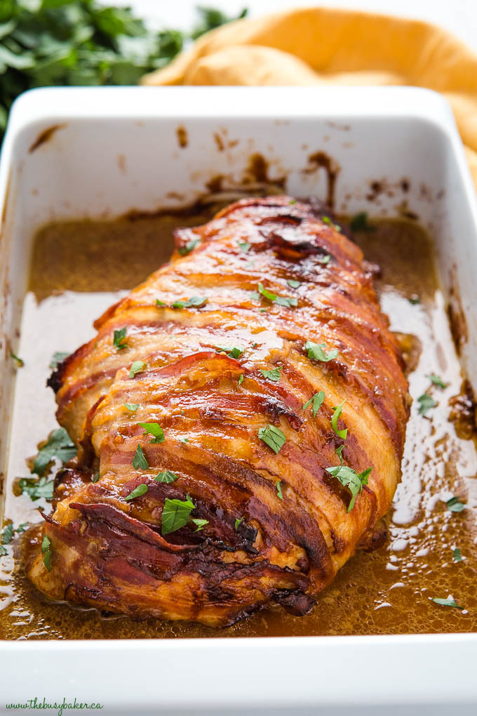 bacon wrapped turkey breast in white pan with juices