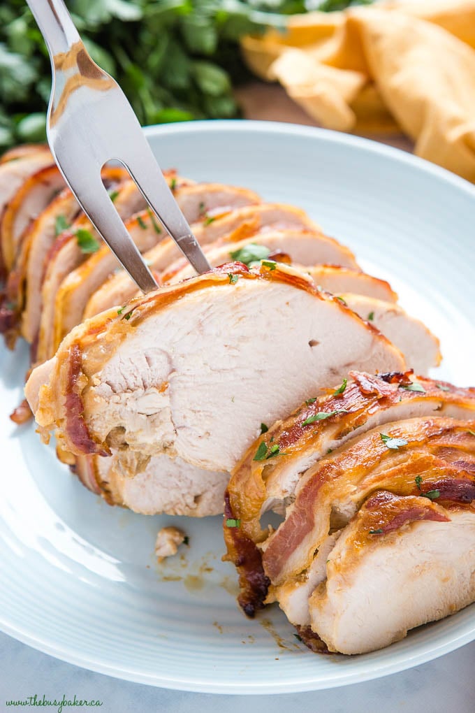 fork holding slice of bacon wrapped roast turkey