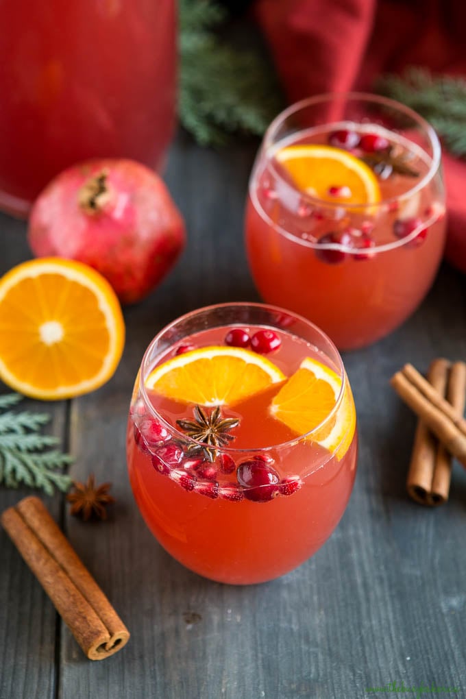 Christmas champagne punch in 2 clear drinking glasses garnished with oranges and star anise