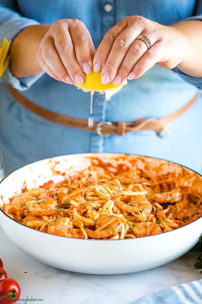 woman squeezing lemon over simple seafood marinara linguine