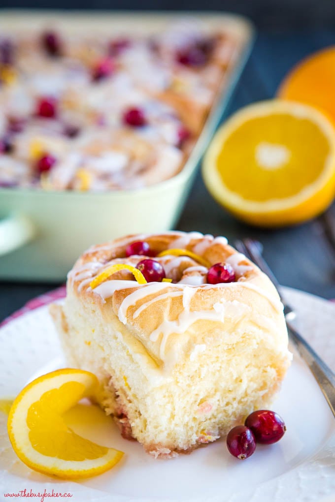 sweet roll on white plate with orange and cranberries