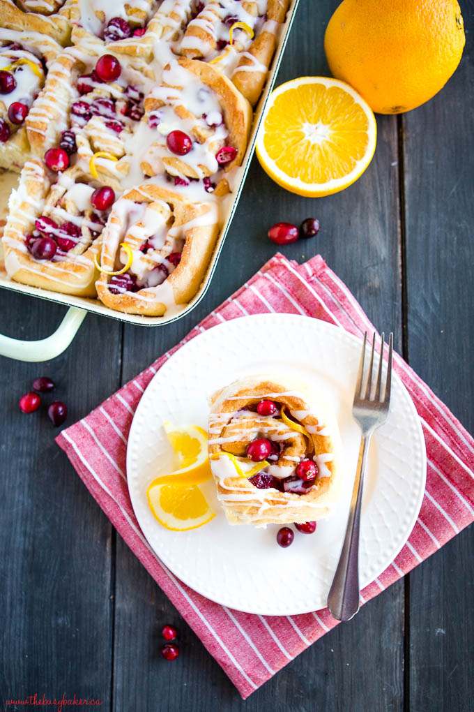 sweet roll on white plate with cranberries and oranges