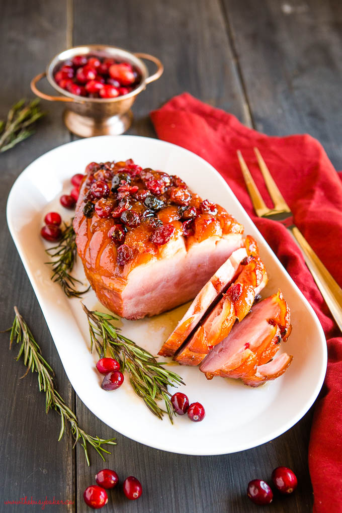 sliced holiday ham with cranberries and rosemary