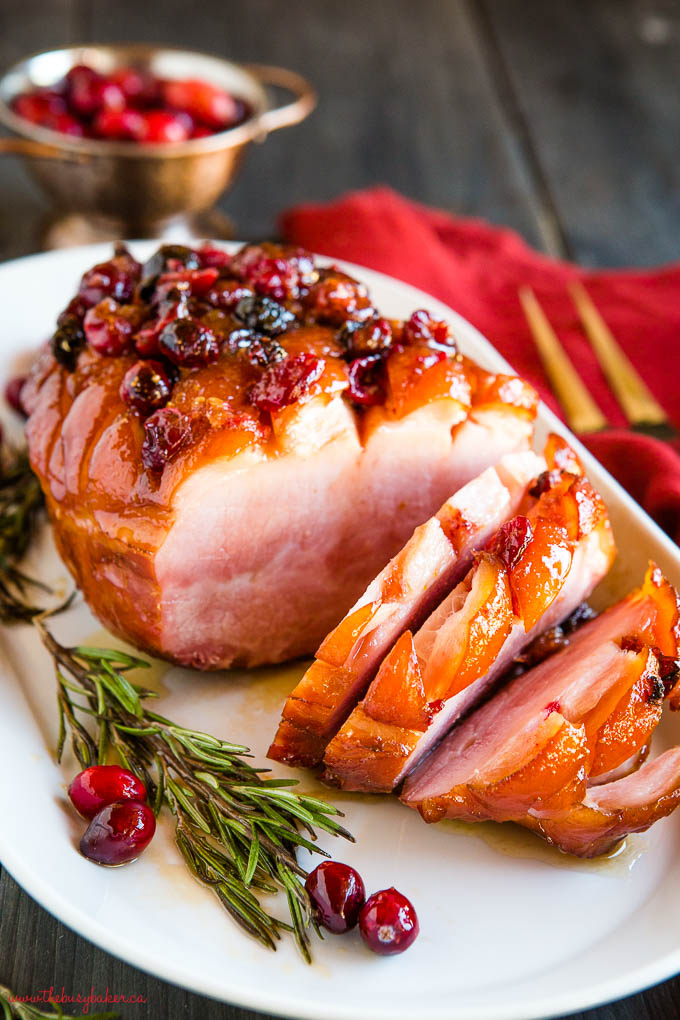 sliced holiday ham with cranberries and maple glaze