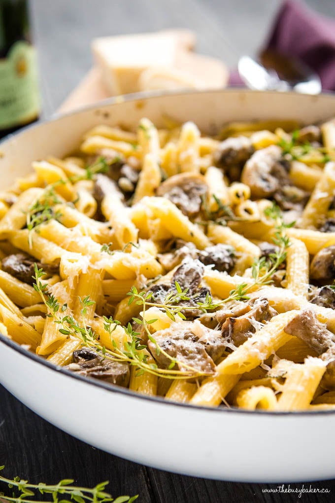 creamy mushroom pasta with fresh herbs in white pan