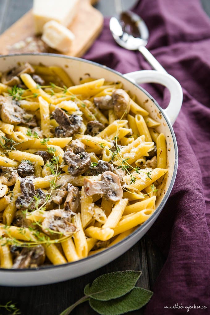 creamy mushroom pasta in white cast iron pan with herbs