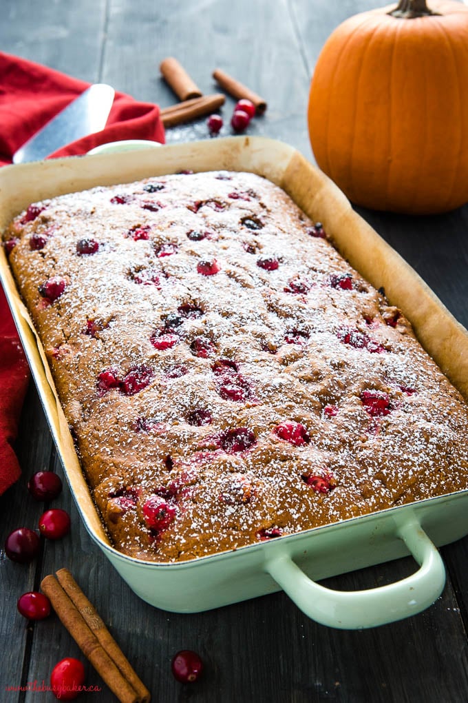 pumpkin cranberry cake with powdered sugar in green pan