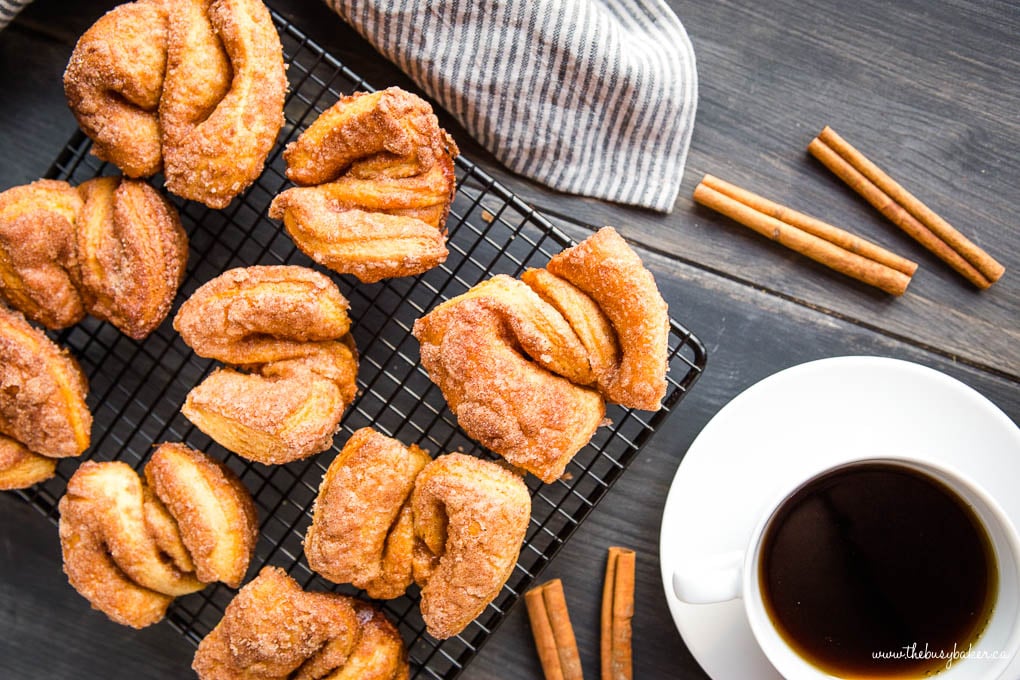 overhead photo: homemade cinnamon sugar twist donuts next to a cup of coffee