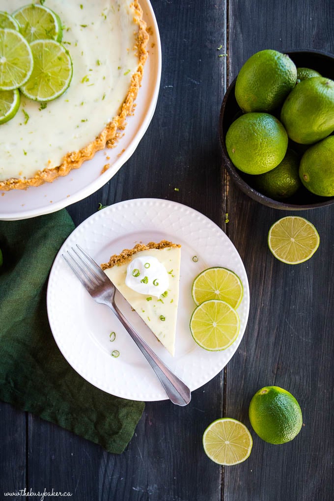 slice of key lime pie on white plate with limes