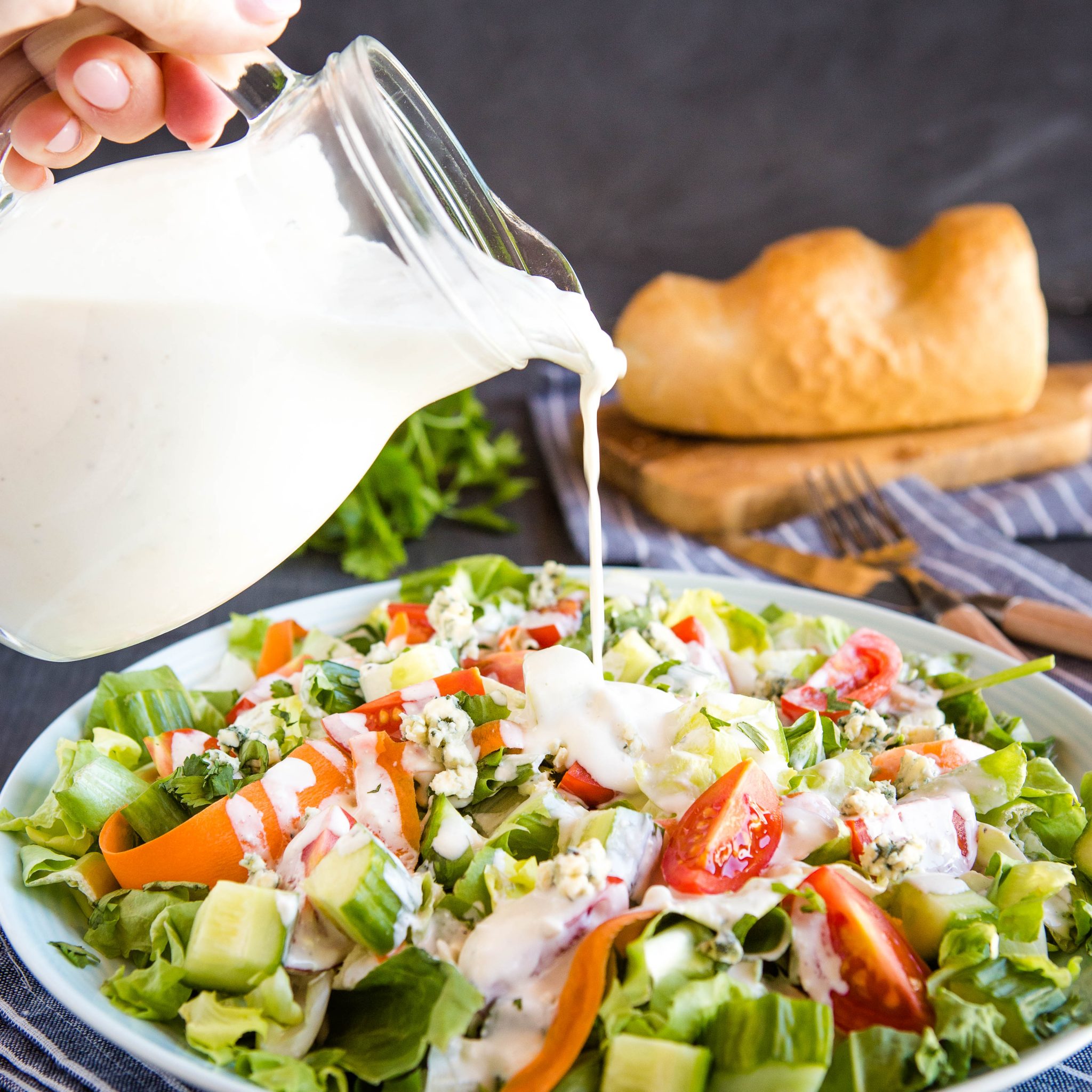 pouring blue cheese dressing onto a salad