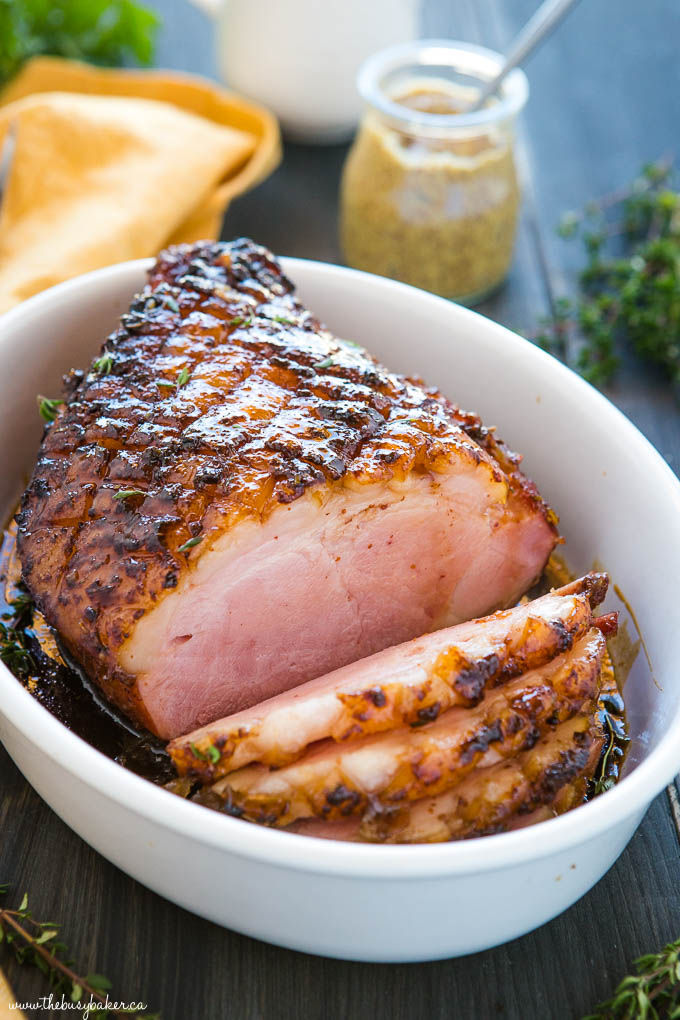 the perfect holiday ham cut into slices in white serving dish