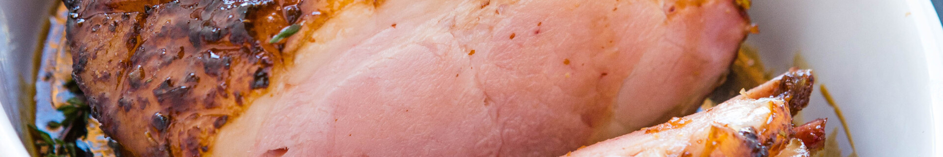 maple glazed ham in white dish, cut into slices