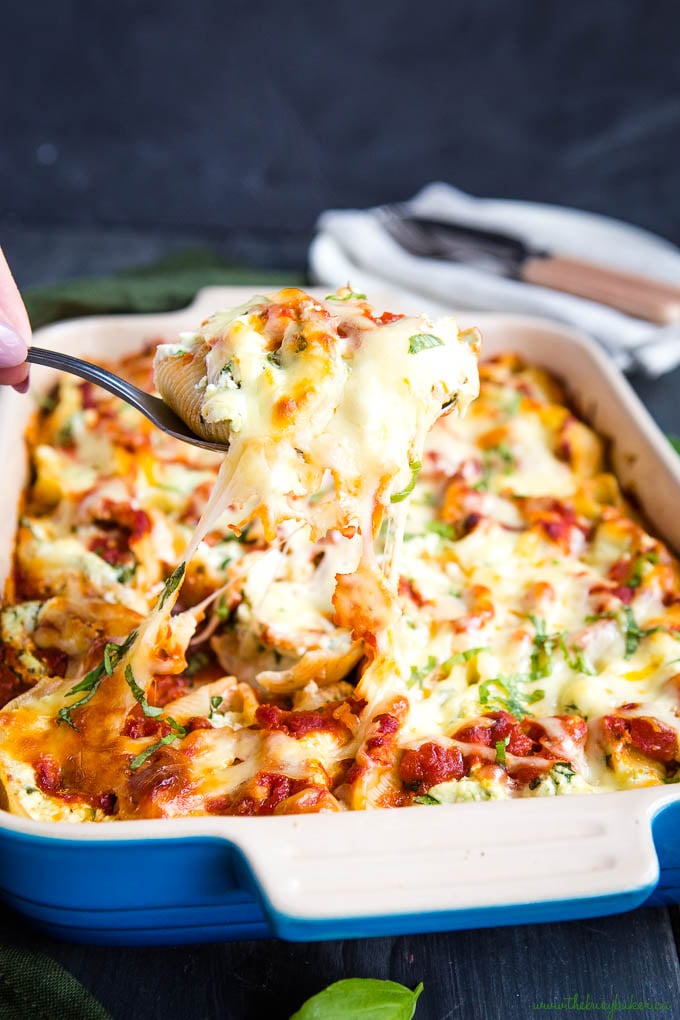 removing serving spoon of ricotta stuffed shells from blue casserole dish