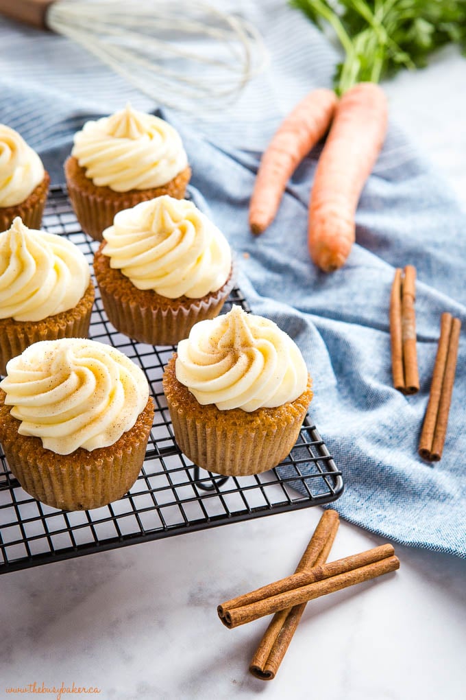 carrot cake cupcakes on wire rack with cinnamon sticks and carrots