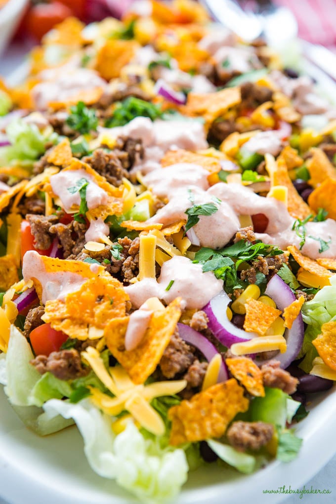 close up image of beef taco salad with lettuce, cheese, onion, beef and Doritos