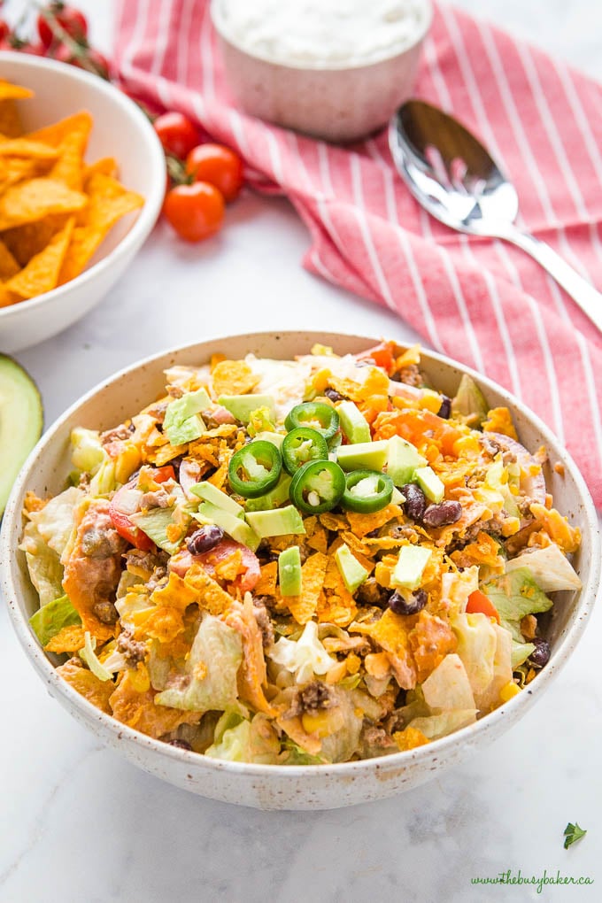 ground beef taco salad in bowl with crunchy tortilla chips and jalapenos on top