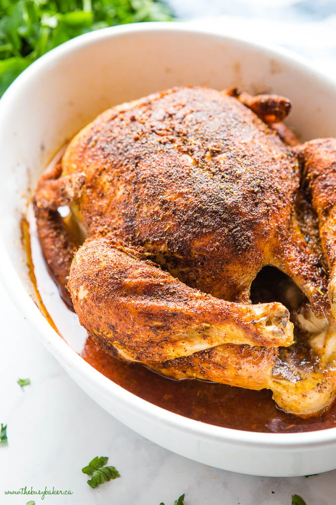 golden brown roast chicken coated in spices, in baking dish