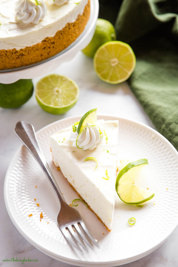 slice of no bake key lime cheesecake on white plate with lime slices