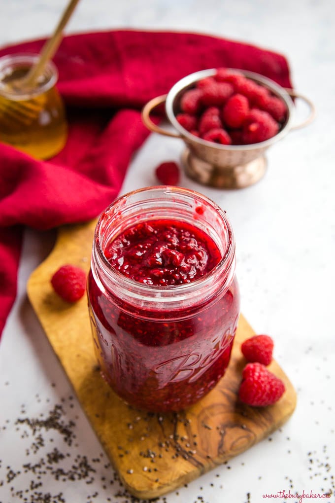 chia seed raspberry jam in mason jar with honey and fresh raspberries