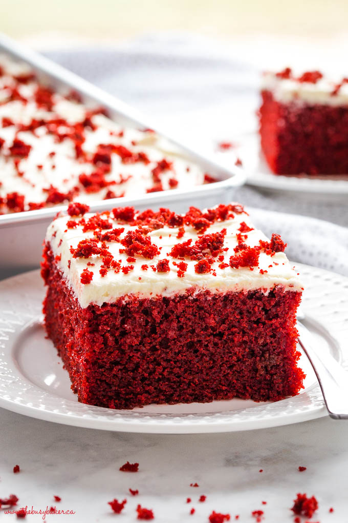 serving of homemade red velvet cake on white plate with cream cheese frosting