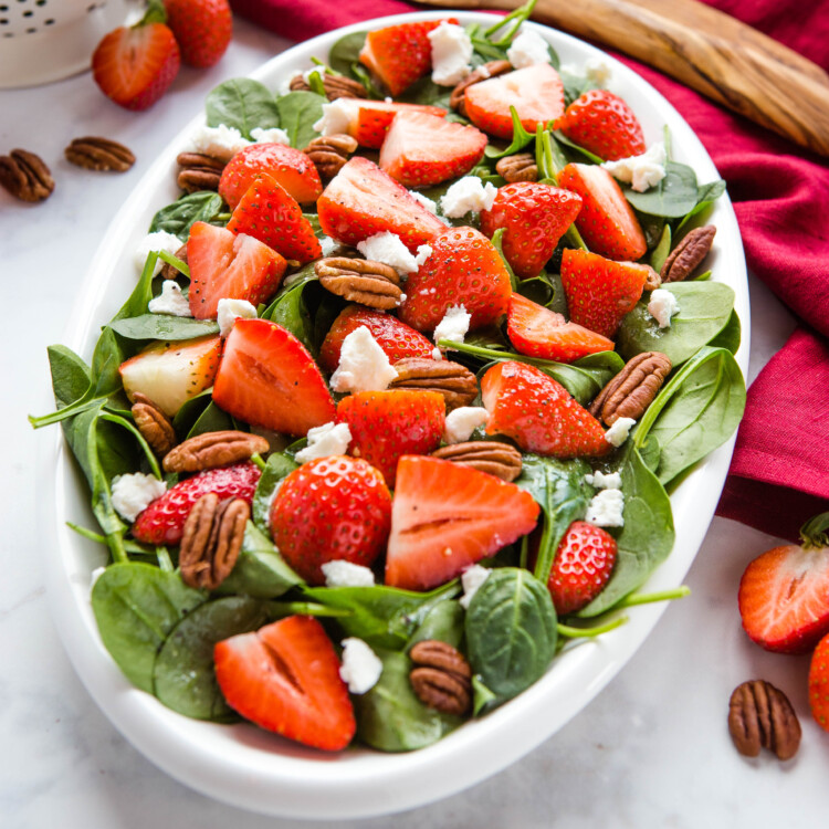 white bowl of strawberry spinach salad with lemon poppy seed dressing