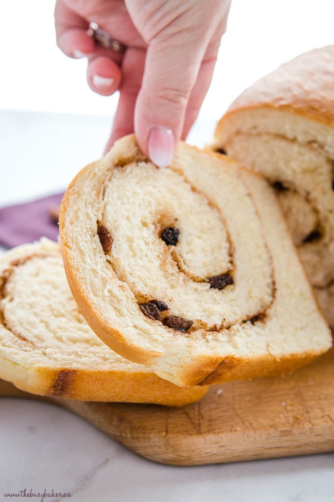 hand reaching for a slice of cinnamon raisin bread