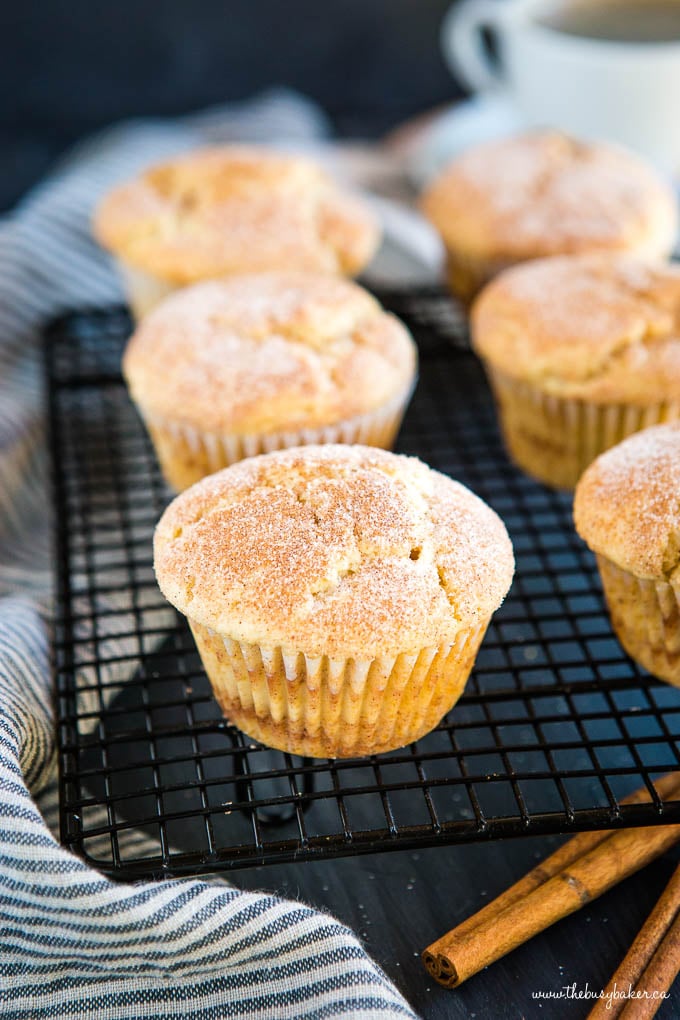 six cinnamon muffins topped with cinnamon sugar on black wire cooling rack